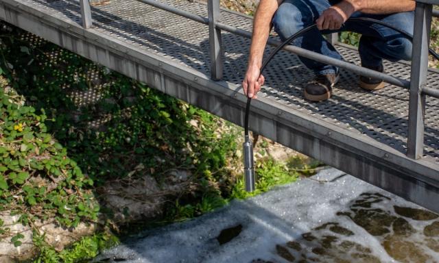 Medewerker IMD doet meting bij waterschap.